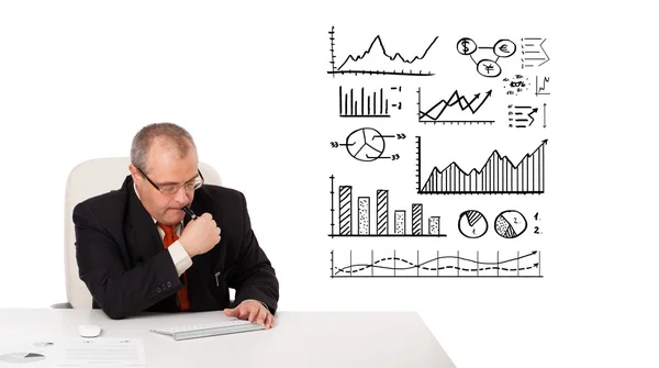 Бизнесмен сидит за столом со статистикой и графиками — стоковое фото