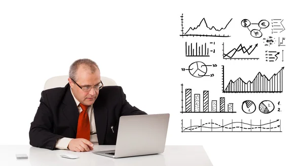 Empresario sentado en el escritorio con diagramas y portátil —  Fotos de Stock