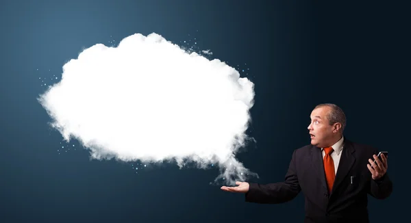 Empresário engraçado em terno segurando um telefone e apresentando nuvem abstrata — Fotografia de Stock