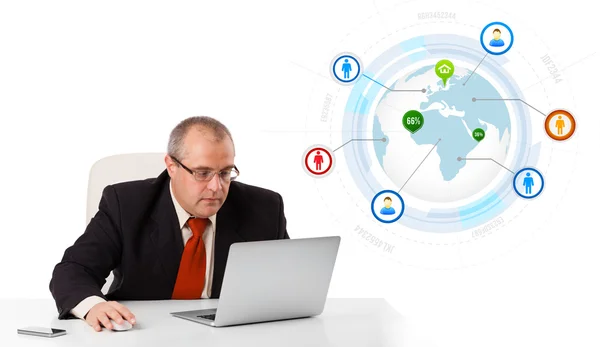 Businessman sitting at desk and looking laptop with globe and so Stock Photo