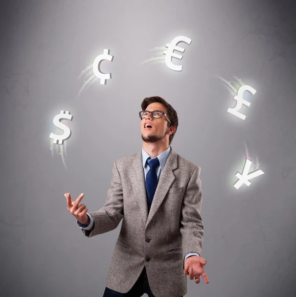 Jonge man permanent en jongleren met valuta pictogrammen — Stockfoto