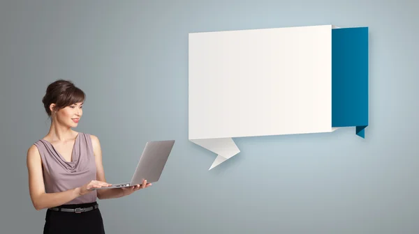 Attractive woman holding a laptop and presenting modern origami — Stock Photo, Image