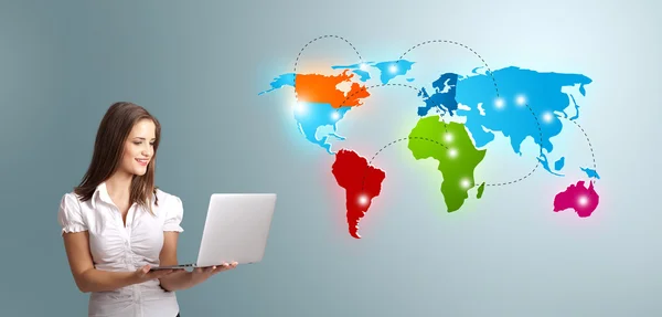 Young woman holding a laptop and presenting colorful world map — Stock Photo, Image