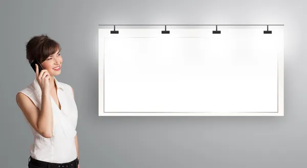 Young woman standing next to a modern copy space and making phon — Stock Photo, Image