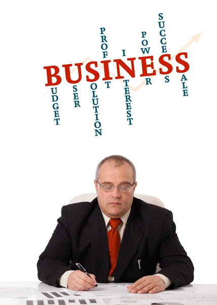 Businessman sitting at desk with word cloud — Stock Photo, Image