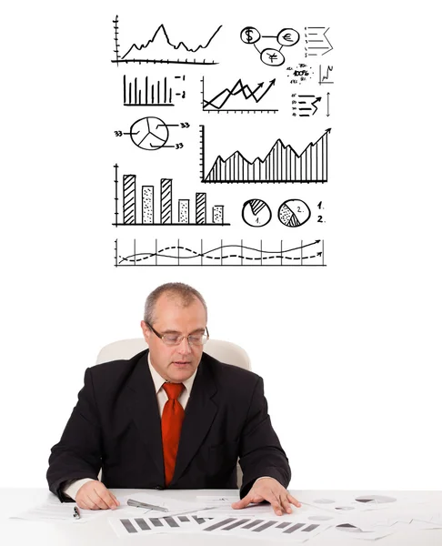 Podnikatel sedí u stolu s statistiky a grafy — Stock fotografie