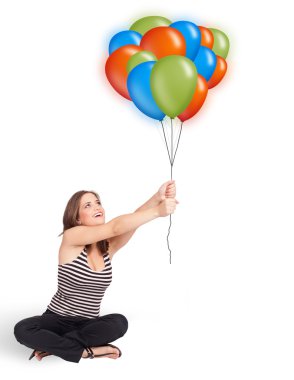 Genç bir kadın elinde renkli balonlar tutuyor.