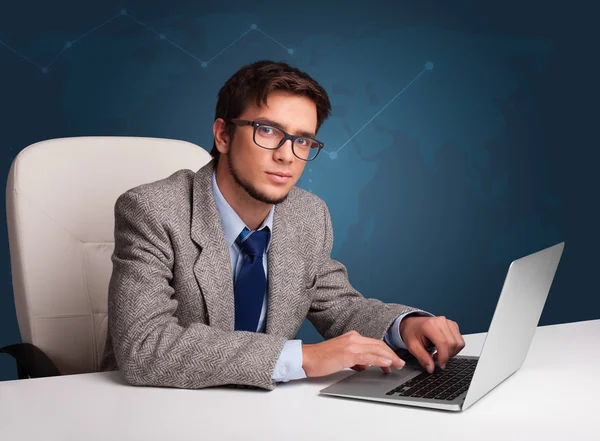 Jongeman zit achter het bureau en typt op laptop — Stockfoto