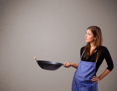 Genç bayan elinde kızartma tavası tutuyor.