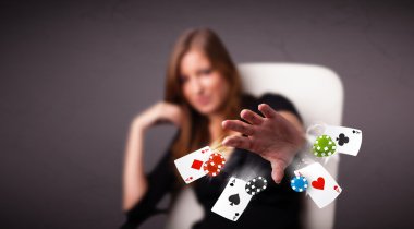 Poker kartları ve fişlerle oynayan genç bir kadın.