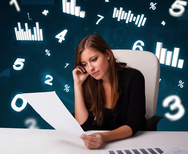 Jeune femme d'affaires assise au bureau avec des diagrammes et des statistiques — Photo