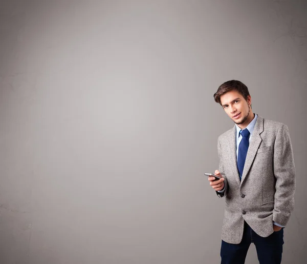 Chico guapo de pie y sosteniendo un teléfono — Foto de Stock