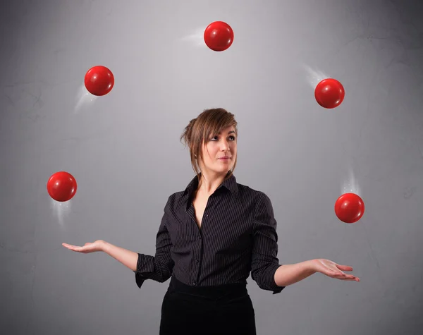 Молодая девушка стоит и жонглирует красными шариками — стоковое фото