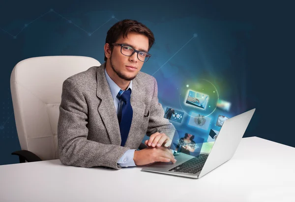 Young man sitting at desk and watching his photo gallery on lapt — Stock Photo, Image