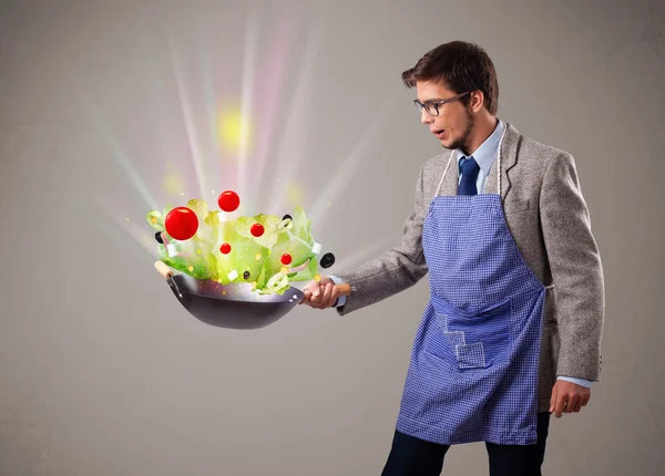 Jeune homme cuisine des légumes frais — Photo