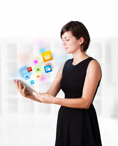 Young woman looking at modern tablet with colourful icons — Stock Photo, Image