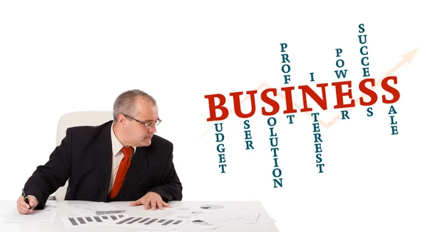 Businessman sitting at desk with word cloud — Stock Photo, Image