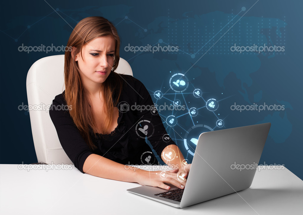 Young lady sitting at desk and typing on laptop with social netw