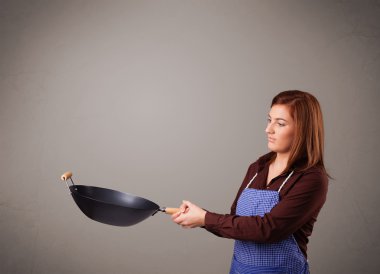 Genç bayan elinde kızartma tavası tutuyor.