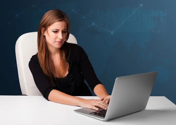 Jonge vrouw zit aan het bureau en typt op laptop — Stockfoto