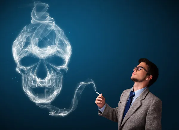 Young man smoking dangerous cigarette with toxic skull smoke — Stock Photo, Image