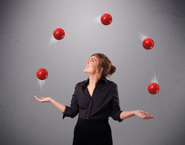 young girl standing and juggling with red balls