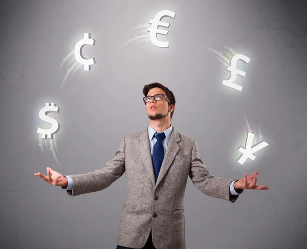 Young man standing and juggling with currency icons — Stock Photo, Image