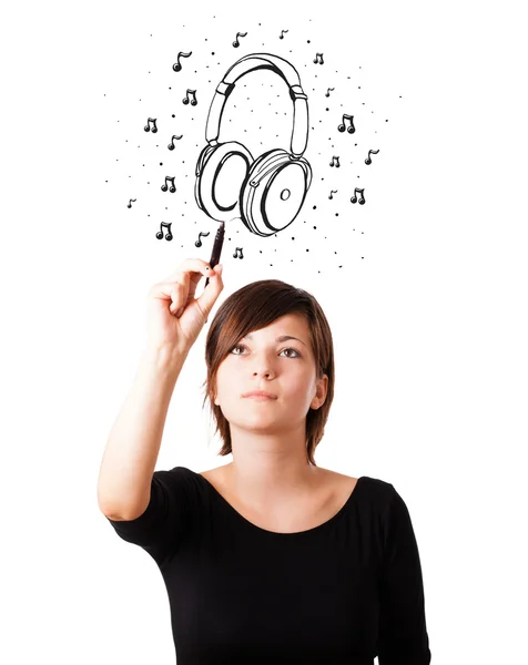 Chica joven dibujando auriculares y notas musicales — Foto de Stock