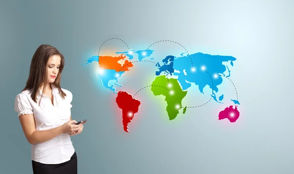 Young woman holding a phone and presenting colorful world map — Stock Photo, Image