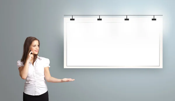 Young woman standing next to a modern copy space and making phon — Stock Photo, Image