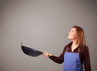 Genç bayan elinde kızartma tavası tutuyor.