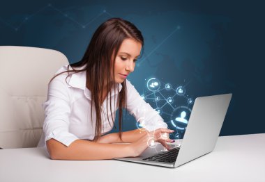 masada oturan ve sosyal şebeke ile laptop tipik genç bayan