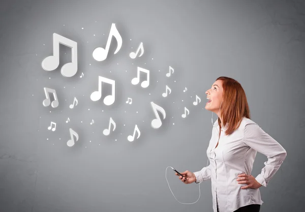 Jolie jeune femme chantant et écoutant de la musique avec n musical — Photo