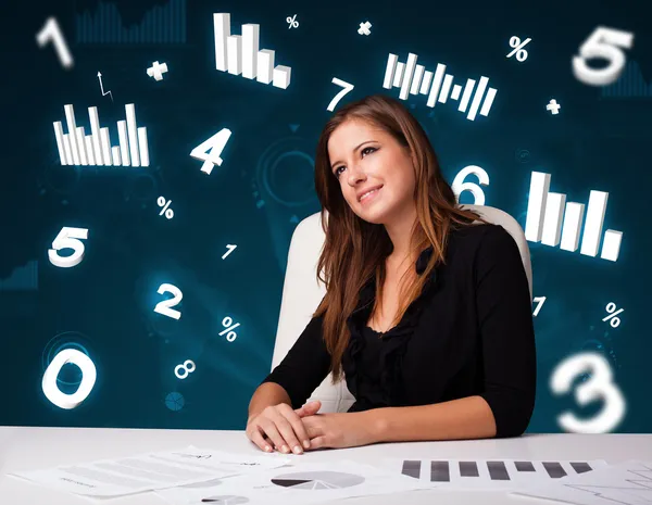 Молодая деловая женщина сидит за столом с диаграммами и статистикой — стоковое фото