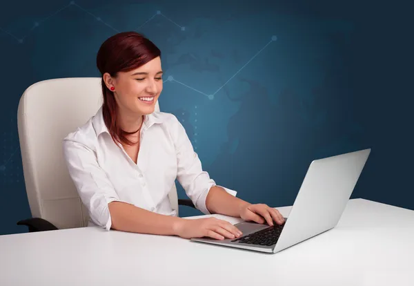 Young woman sitting at desk and typing on laptop — Stock Photo, Image
