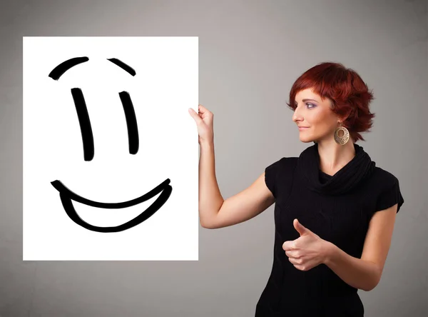 Jovem mulher segurando sorridente desenho rosto — Fotografia de Stock