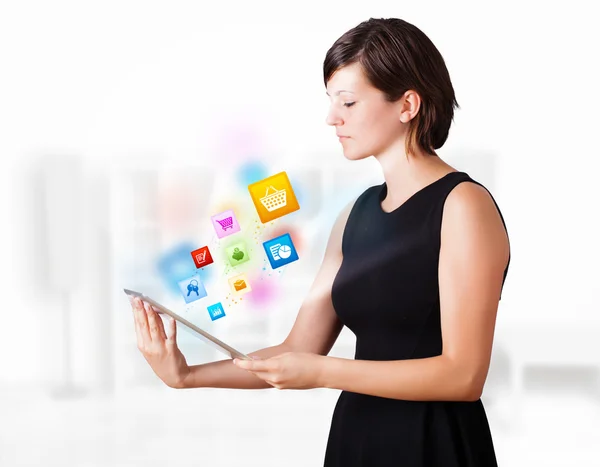 Jovem mulher olhando para tablet moderno com ícones coloridos — Fotografia de Stock