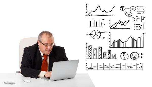 Affärsman som sitter vid skrivbord med diagram och laptop — Stockfoto
