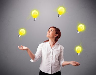 Genç bayan ayakta ve ampullerle hokkabazlık yapıyor.