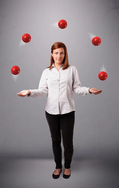 Ung flicka står och jonglerar med röda bollar — Stockfoto