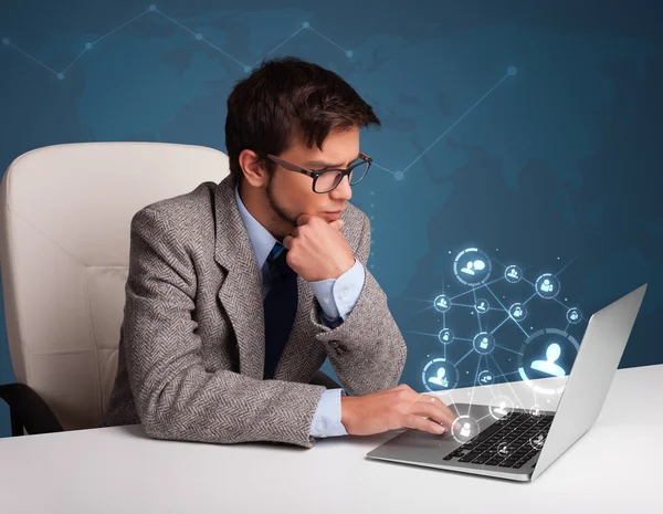 Young man sitting at desk and typing on laptop with social netwo — Stock Photo, Image