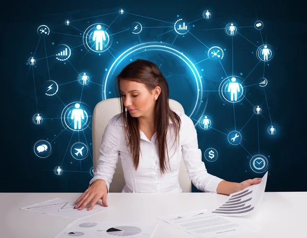 Bizneswoman siedzi przy biurku z ikonami sieci społecznościowych — Zdjęcie stockowe