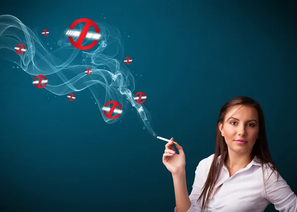 Young woman smoking dangerous cigarette with no smoking signs — Stock Photo, Image