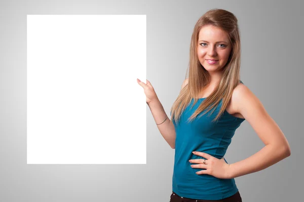 Ung kvinna som presenterar vit papperskopia utrymme — Stockfoto