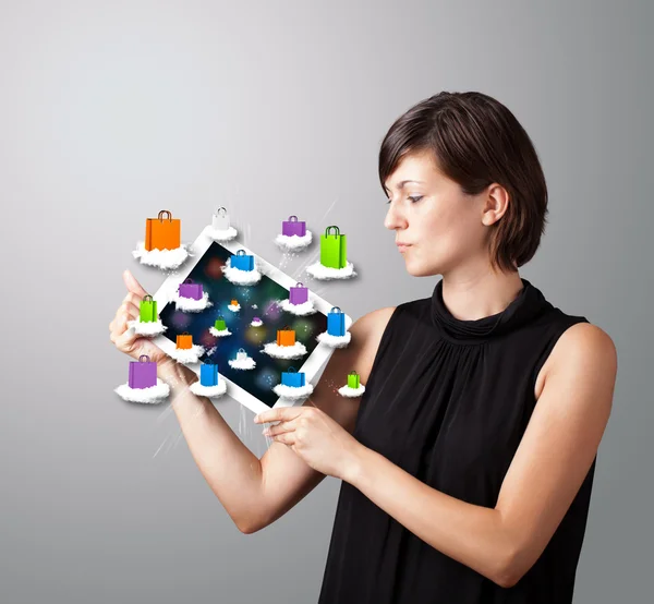 Женщина держит современный планшет с красочными мешками для покупок на облаке — стоковое фото