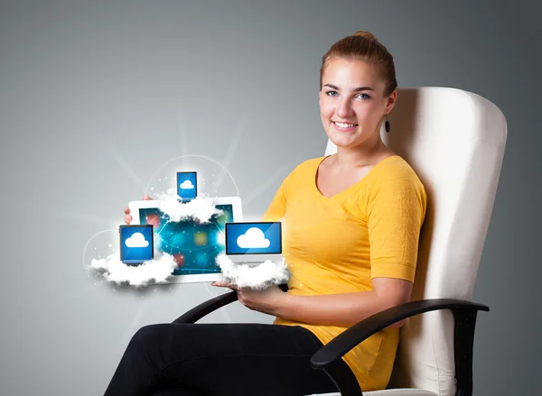 Junge Frau hält Tablet mit modernen Geräten in den Wolken — Stockfoto