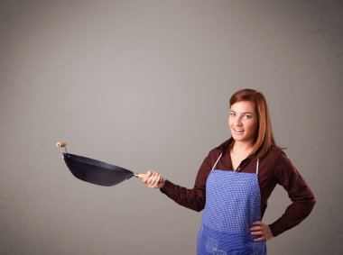 Genç bayan elinde kızartma tavası tutuyor.