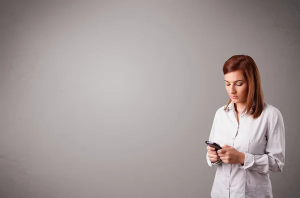 Jovem senhora de pé e segurando um telefone com espaço de cópia — Fotografia de Stock