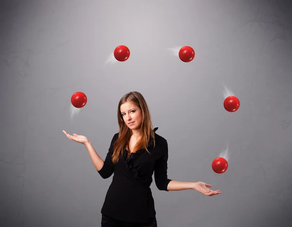 Young girl standing and juggling with red balls — Stock Photo, Image