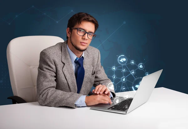 Jovem sentado na mesa e digitando no laptop com rede social — Fotografia de Stock